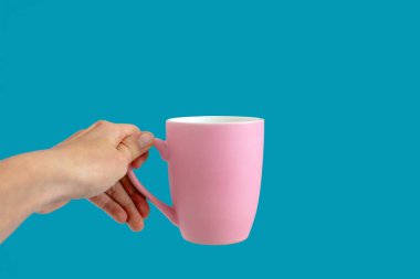 Mavi arka planda pembe bardak tutan kişi