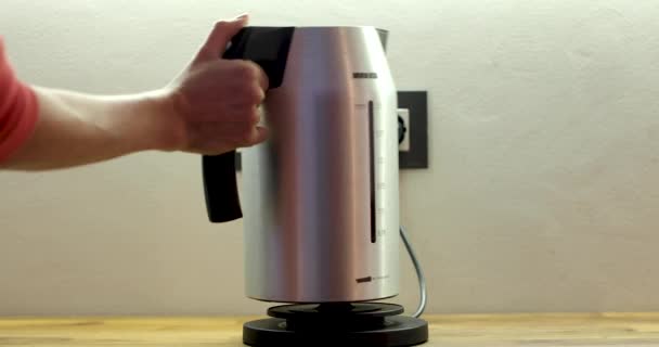 Людина кладе електричний чайник на чорну підставку — стокове відео