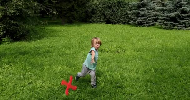 Liten unge leker med röd bumerang utomhus — Stockvideo