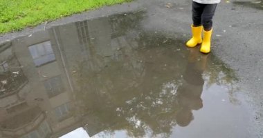 Bebek sarı lastik çizmeler su birikintileri ile stomping