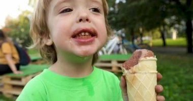 Kirli el çikolatalı dondurma zevk ile neşeli çocuk