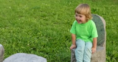 Parkta taş sandalyede oturan çocuk