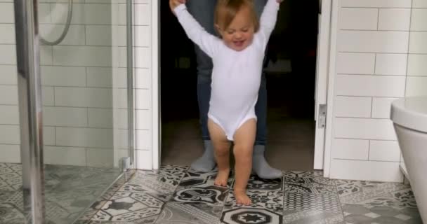 Pequeno bebê fazendo primeiros passos com ajuda de adultos — Vídeo de Stock