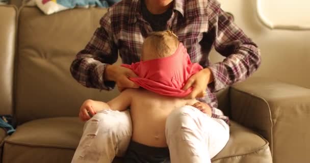Неузнаваемый родитель одевает маленького ребенка в футболку — стоковое видео