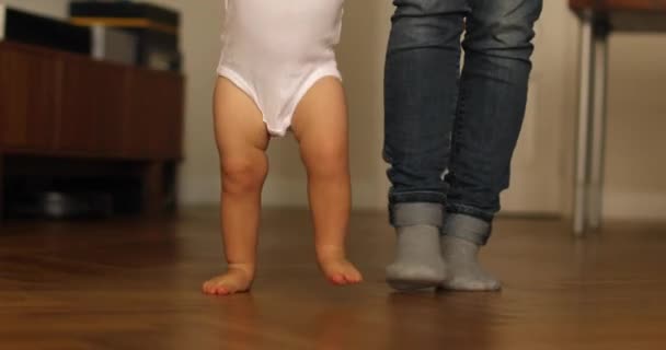 Små fötter går på golvet. Närbild av bebis lärande promenad — Stockvideo