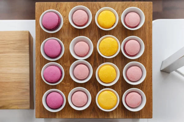 Macaron multicolore in tazze servito su vassoio di legno — Foto Stock