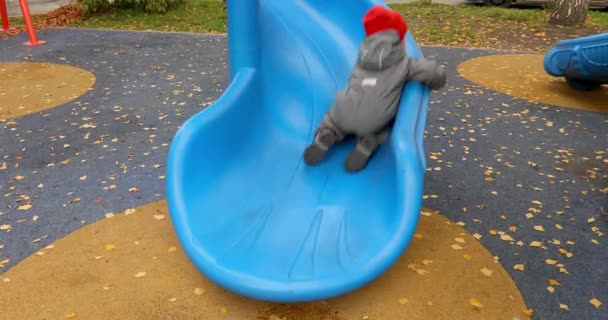 Glad liten pojke glidande på lekplats — Stockvideo