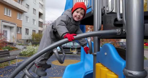 Маленький хлопчик піднімається по сходах на дитячому майданчику — стокове відео