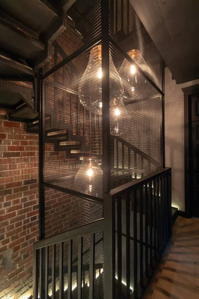 Giant pendant lamps among spiral staircase against brown brick wall — Stock Photo, Image