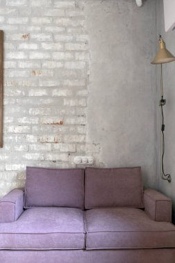 Pembe kanepe beyaz tuğlaya ve sıvanmış duvara karşı.