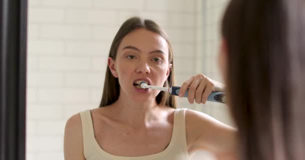 Mulher bonita escovando dentes olhando no espelho — Vídeo de Stock