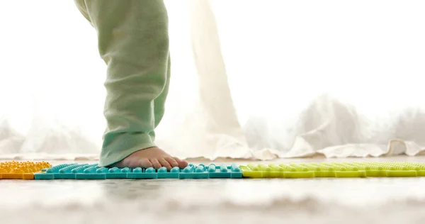 Ребенок на массажном коврике делает упражнения для профилактики плоскостопия — стоковое фото
