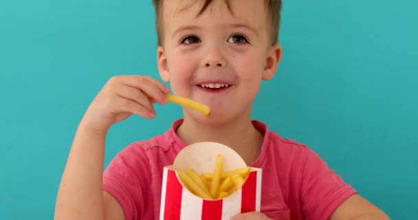 Niño en el interior comiendo pescado y papas fritas sonriendo — Vídeos de Stock