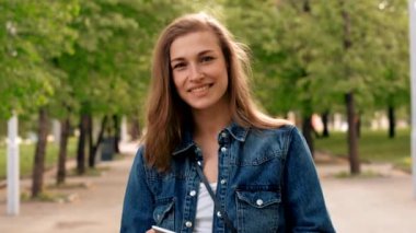 Parkta kaldırımda duran akıllı telefonlu mutlu kadın.