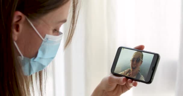 Zamaskowana kobieta rozmawiająca przez telefon wideo ze swoim przyjacielem — Wideo stockowe
