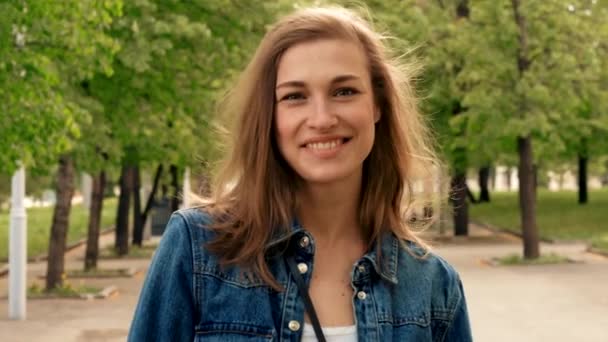 Щаслива жінка зі смартфоном, що стоїть на тротуарі в парку — стокове відео