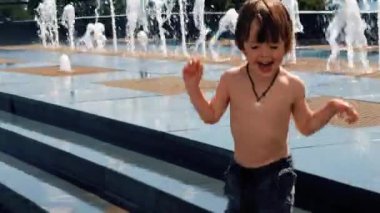 Neşeli çocuk yazın çeşmenin yanında oynuyor.