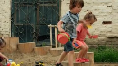 Küçük çocuklar kumlu oyun bahçesinde oynuyorlar