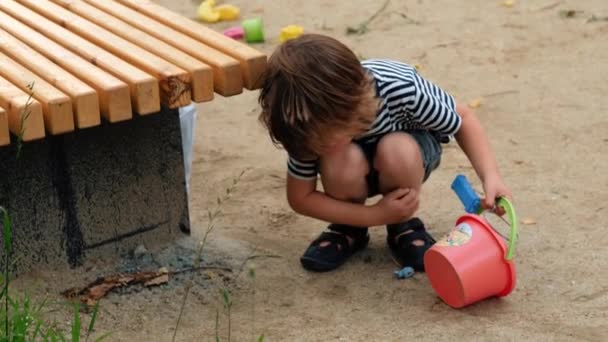 Malé dítě si hraje s plastovými hračkami na ulici — Stock video