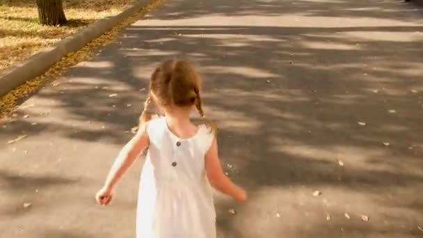 Маленькая девочка бежит по улице с видом сзади — стоковое видео