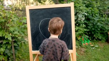 Çocuk tahtaya çiziyor.