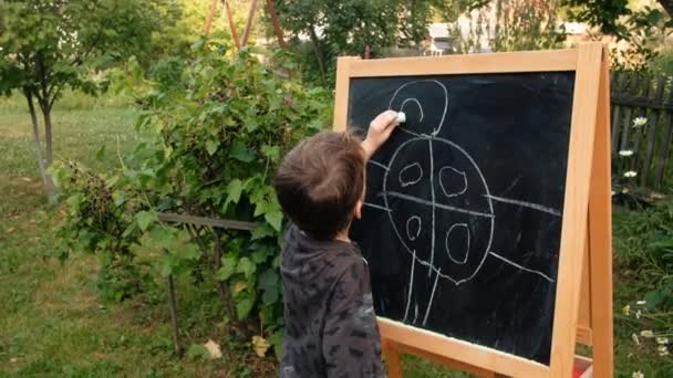 A criança desenha no quadro negro — Vídeo de Stock