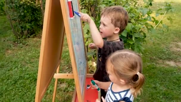 Niños dibujan con tiza sobre un fondo blanco pizarra — Vídeos de Stock