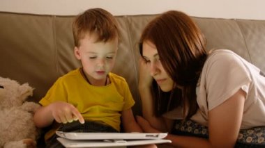Anne ve oğlu kanepede tablet kullanıyor.