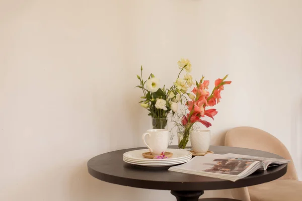 Bloemen en tijdschrift in de buurt van vaatwerk op tafel — Stockfoto