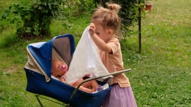 Schattig klein meisje met haar speelgoed rijtuig — Stockvideo