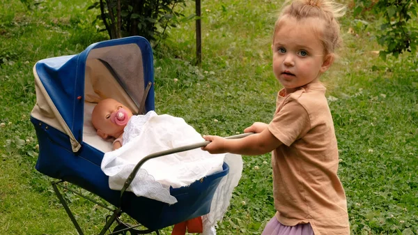 Cute little girl with her toy carriage — Stock Photo, Image