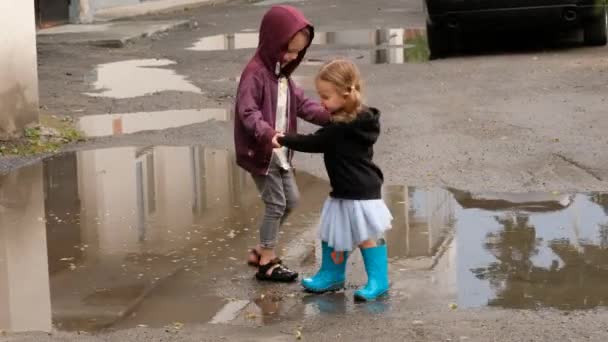 Broers en zussen dansen bij plassen op straat — Stockvideo