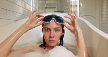 Maskeli kadın küvete dalıyor.