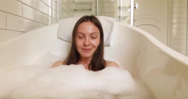 Mutlu kadın köpüklü banyo yapıyor.