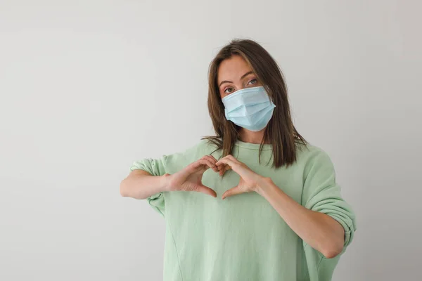 Woman in medical mask hands heart