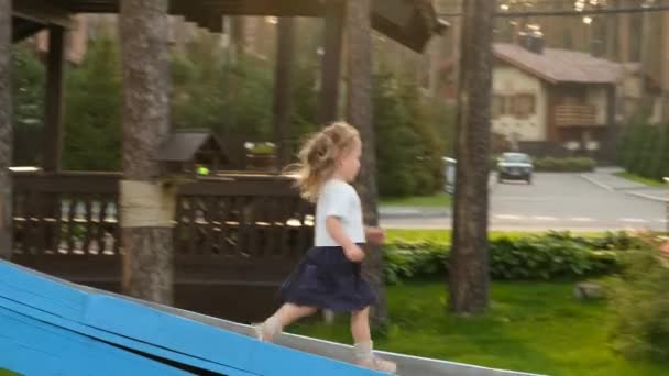 Menina corre para baixo slide e retorna no playground — Vídeo de Stock