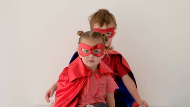 Süper kahraman kostümlü komik çocuk kız kardeşine sarılıyor ve onu öpüyor. — Stok video