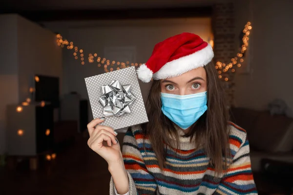 Женщина в маске показывает рождественский подарок — стоковое фото