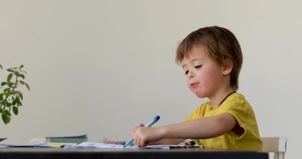 Χαμογελώντας μικρό αγόρι στο τραπέζι κλήρωση με μαρκαδόρους σε λευκό — Αρχείο Βίντεο