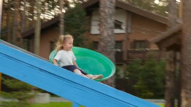 Kleine jongen lanceert zus te glijden in de tuin van het landhuis — Stockvideo