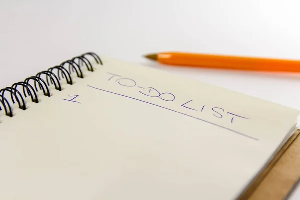 To do list in spiral notepad. White background, flat lay style.