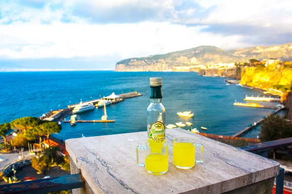 Sorrento, İtalya - 7 Mart 2018: Şişe ve geleneksel İtalyan likör limon ile iki bardak - Lemonchello - Sorrent'ın sahil arka plan üzerinde 
