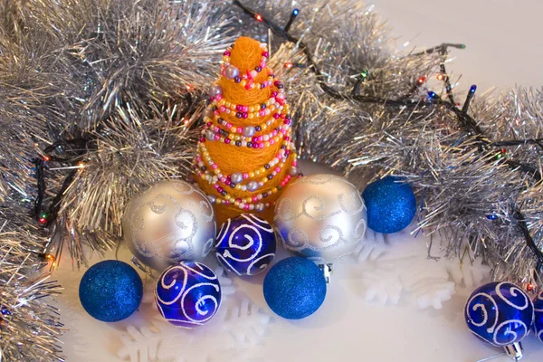 Elegant composition with Orange Christmas Handmade Tree with blue, silver baubles and silver decoration on the white background
