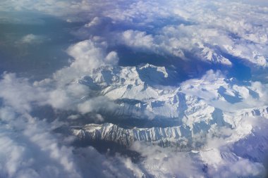 Güzel gökyüzü güneşli günde kar Dağları üzerinden bir uçak ile bulutların üzerinde görünümünü