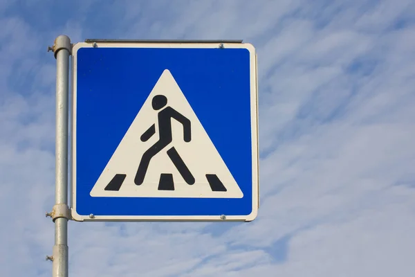 Pedestrian crossing sign in front of blue sky