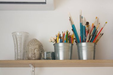 Kurşun kalem, fırça ve Buda baş artist's Studio ile ahşap raf