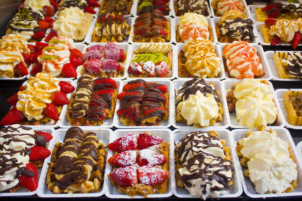 Traditional tasty sweet fragrant Belgian Waffles decorated by strawberries, kiwi, banana and cream in Brussels