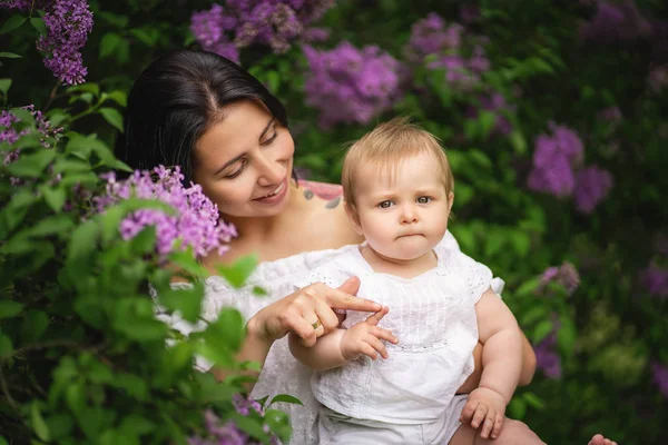 Bella giovane madre e figlia vicino alla fioritura lilla . — Foto Stock