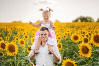 Mutlu kızı ayçiçeği alanında babasının omuzlarında oturur