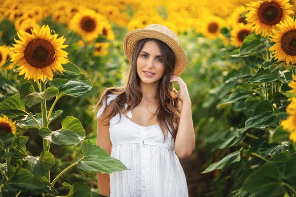 Retrato ao ar livre de jovem bela menina sorridente feliz usando chapéu de palha. posando no campo de girassol — Fotografia de Stock